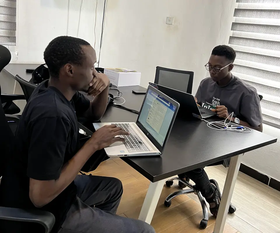 Two members of the Synoloop team working on laptops in our Lagos office
